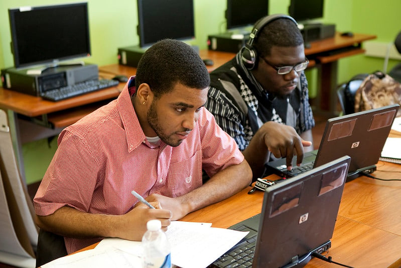 Adult students learning cloud engineering on laptops